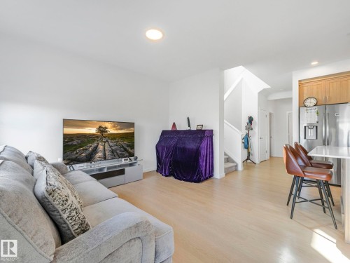 Open-concept living space featuring light wood-finish flooring, recessed lighting, and a white countertop island with seating - 4851 Kinney Road, Edmonton, AB - Indoor Photo Showing Living Room