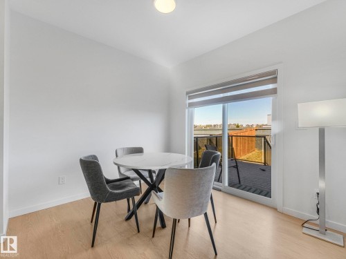 Dining area with wood-finish flooring, white baseboards, and a sliding glass door leading to an outdoor deck - 4851 Kinney Road, Edmonton, AB - Indoor Photo Showing Dining Room