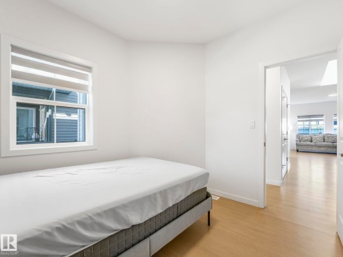 Room featuring light wood-finish flooring, a white-framed window with a horizontal blind, and white painted walls - 4851 Kinney Road, Edmonton, AB - Indoor Photo Showing Bedroom