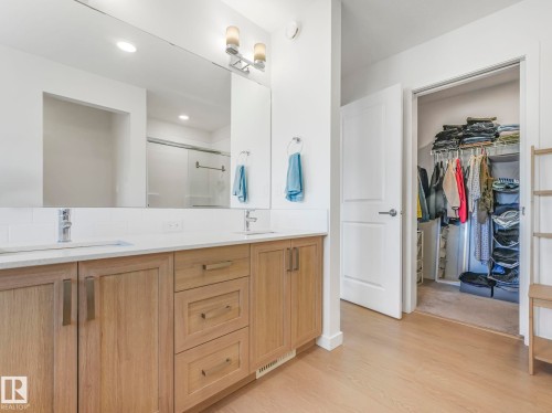 Spacious bathroom featuring a double vanity with light wood-finish cabinetry, white countertops, and dual vessel sinks - 4851 Kinney Road, Edmonton, AB - Indoor Photo Showing Bathroom