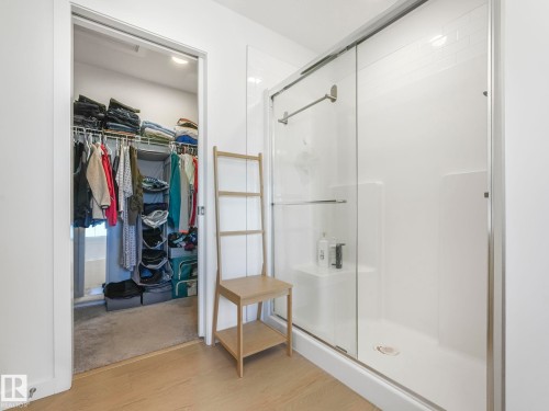 Shower enclosure with sliding glass doors, integrated shelving, and white subway tile-patterned wall panels - 4851 Kinney Road, Edmonton, AB - Indoor