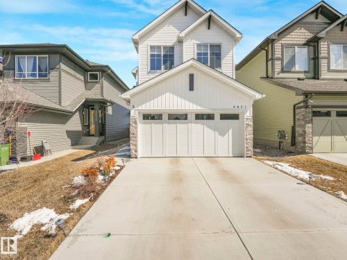 White two-story residence featuring vertical and horizontal siding, stone accents, and a two-car garage - 4851 Kinney Road, Edmonton, AB - Outdoor With Facade