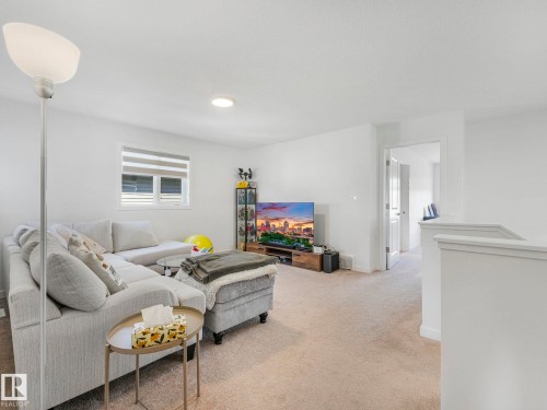 Carpeted living area featuring a large window with blinds, recessed ceiling lighting, and a white interior door - 4851 Kinney Road, Edmonton, AB - Indoor Photo Showing Living Room