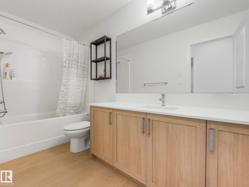 Bathroom vanity with wood-finish cabinetry, white countertop, and integrated sink - 4851 Kinney Road, Edmonton, AB - Indoor Photo Showing Bathroom