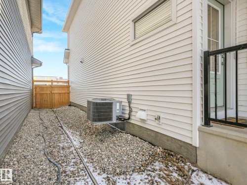 Side yard featuring gravel landscaping, a wooden fence, and an air conditioning unit - 4851 Kinney Road, Edmonton, AB - Outdoor With Exterior