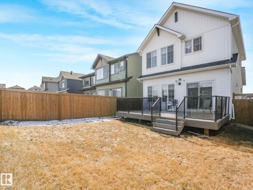 Rear exterior featuring a multi-level deck with glass panel railings, direct yard access, and white horizontal and vertical siding - 4851 Kinney Road, Edmonton, AB - Outdoor With Deck Patio Veranda