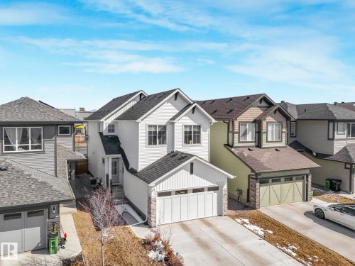 Modern suburban residence featuring a white siding exterior, dark shingle roofing, and an integrated two-car garage with a white door - 4851 Kinney Road, Edmonton, AB - Outdoor