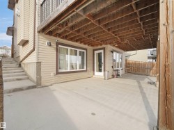 The property features a concrete patio area, accessible via a glass-paneled door, with additional windows visible on the exterior wall - 