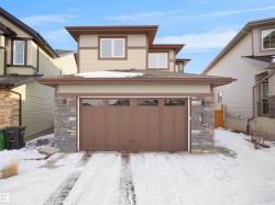 The property features a two-story exterior with light-colored siding and a brown garage door - 