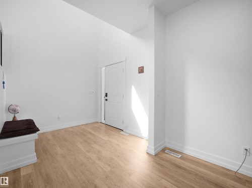 The property features light-toned hardwood flooring, white walls, and a white entrance door - 4231 Charles Close, Edmonton, AB - Indoor Photo Showing Other Room