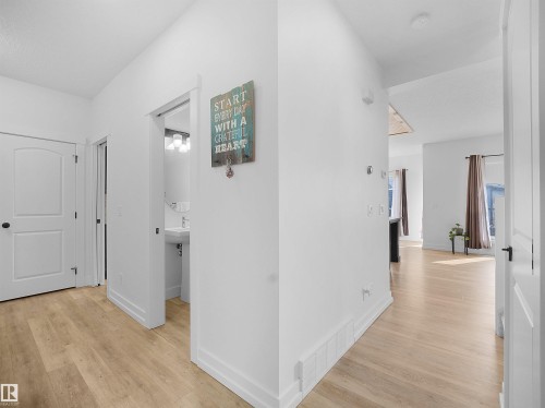 The property features light-colored flooring, white interior doors, and a well-lit hall with a view into another room - 4231 Charles Close, Edmonton, AB - Indoor Photo Showing Other Room