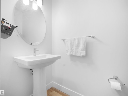 Bathroom featuring a white pedestal sink with a chrome faucet, an oval mirror, and a towel bar - 4231 Charles Close, Edmonton, AB - Indoor Photo Showing Bathroom