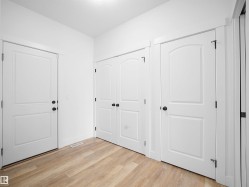 Entryway featuring light-toned flooring, white walls, and multiple white paneled doors with dark hardware - 