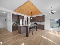 The kitchen features extensive cabinetry, a central island with bar seating, stainless steel appliances, and a tiled backsplash - 