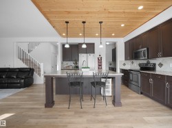 The kitchen features dark wood cabinetry, stainless steel appliances, and a tiled backsplash - 