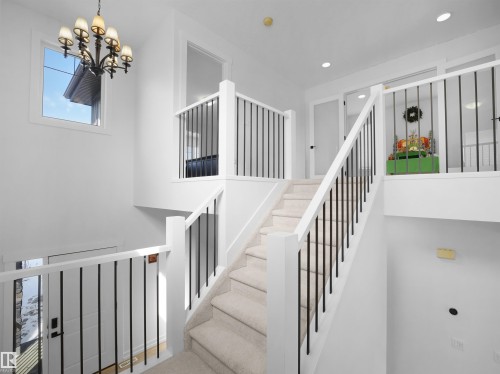 The property features a staircase with carpeted treads and risers, white newel posts, and black balusters - 4231 Charles Close, Edmonton, AB - Indoor Photo Showing Other Room