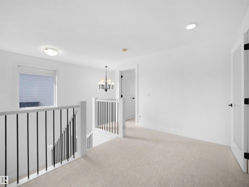 This property features a bright hallway with light-colored carpeting, a window with blinds, and white walls - 4231 Charles Close, Edmonton, AB - Indoor Photo Showing Other Room