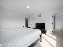 This bright room features white walls, light-colored carpeting, and a ceiling light fixture - 