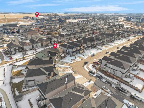 Aerial view of the neighborhood showcasing residential properties with grey roofs and varied exterior finishes, alongside a paved street and surrounding open land - 4231 Charles Close, Edmonton, AB - Outdoor With View