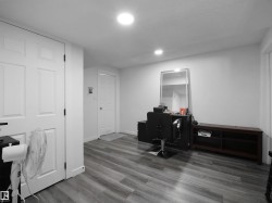 This room features light grey wood-look flooring, recessed lighting, and white walls - 