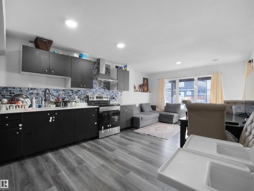 The property features an open concept kitchen and living area with wood-look flooring and recessed lighting - 4231 Charles Close, Edmonton, AB - Indoor Photo Showing Kitchen With Double Sink