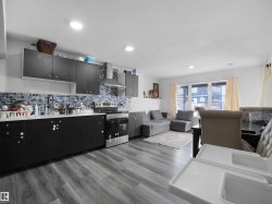 The property features an open concept kitchen and living area with wood-look flooring and recessed lighting - 