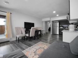 Open concept living area featuring wood plank flooring, a dining area, and a kitchen with stainless steel appliances - 