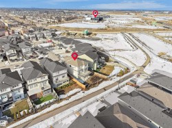 Aerial view of the property and surrounding neighborhood, featuring residential homes with grey roofs and snow-covered ground - 