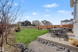 Expansive backyard featuring a concrete patio, a manicured lawn, a horizontal slat fence, and a black metal fence - 