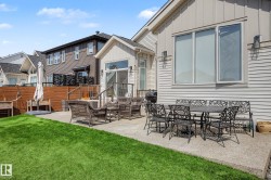 Expansive concrete patio with direct access to interior spaces, bordered by a manicured lawn and a wooden privacy fence - 