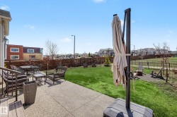 Expansive backyard featuring a concrete patio, lush green lawn, and a perimeter wood fence - 