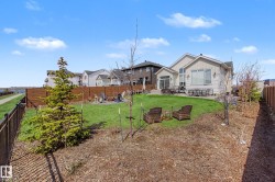 Expansive backyard featuring a large green lawn, a wood fence, and mature landscaping - 