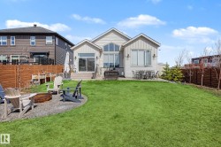 Expansive backyard featuring a manicured lawn, a raised wood deck, a concrete patio, a gravel fire pit area, and a privacy fence - 