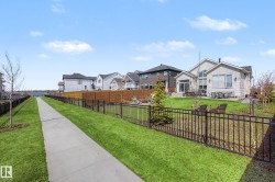 Expansive backyard featuring a manicured lawn, a black wrought-iron fence, and a wooden privacy fence - 
