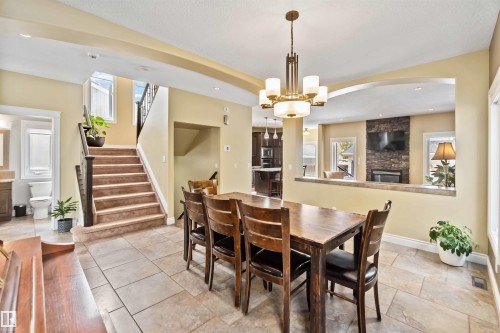 Spacious dining area featuring neutral-toned tile flooring, a multi-light chandelier, and an arched pass-through to the living room - 10630 82 Street, Edmonton, AB - Indoor Photo Showing Dining Room