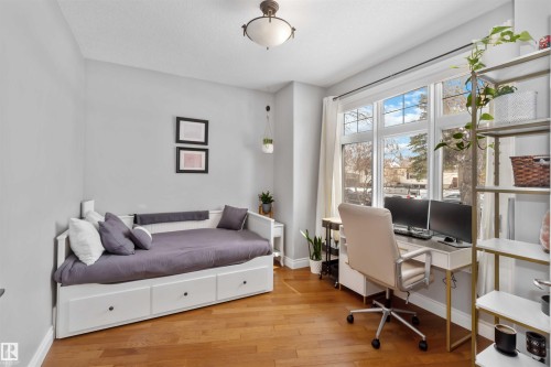 Bright room featuring multiple windows with trim, hardwood flooring, a ceiling-mounted light fixture, and light gray wall paint - 10630 82 Street, Edmonton, AB - Indoor Photo Showing Bedroom
