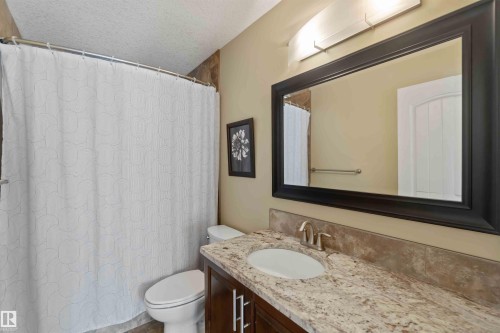 Bathroom featuring a vanity with a granite countertop, undermount sink, and dark wood cabinetry - 10630 82 Street, Edmonton, AB - Indoor Photo Showing Bathroom
