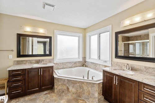 Corner soaking tub surrounded by stone-finish tile - 10630 82 Street, Edmonton, AB - Indoor Photo Showing Bathroom
