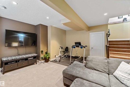 Finished recreational space with neutral carpeting, recessed lighting, and a wall-mounted television - 10630 82 Street, Edmonton, AB - Indoor