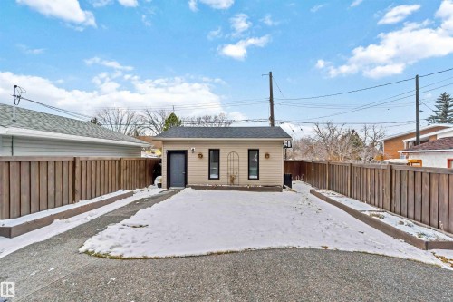 Detached ancillary building featuring a dark entry door, two vertical windows, and light-colored siding - 10630 82 Street, Edmonton, AB - Outdoor