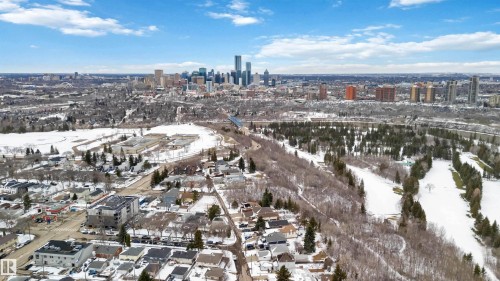 Aerial perspective showcasing residential properties, a golf course with snow-covered fairways, and a distant city skyline - 10630 82 Street, Edmonton, AB - Outdoor With View