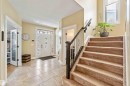 Entry foyer featuring large format tile flooring, a white paneled front door with decorative glass inserts and transom, and a carpeted staircase with a dark wood handrail and wrought iron balusters - 10630 82 Street, Edmonton, AB  - Indoor Photo Showing Other Room 