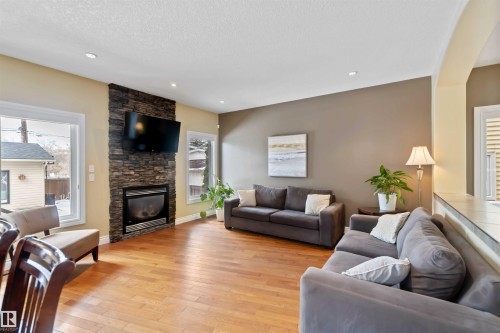 Living area featuring wood-finish flooring, a stacked stone fireplace surround, and recessed lighting - 10630 82 Street, Edmonton, AB - Indoor Photo Showing Living Room With Fireplace