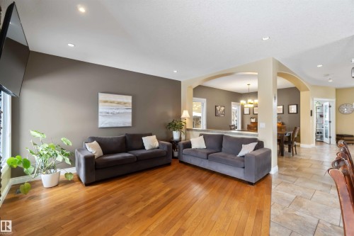 Open-concept living area featuring warm wood-finish flooring, recessed lighting, and elegant arched doorways - 10630 82 Street, Edmonton, AB - Indoor Photo Showing Living Room
