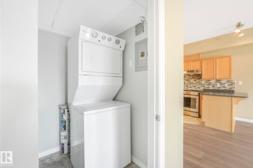 Laundry room with stacked washer / dryer, light wood finished floors, and electric panel - 310 10606 102 Avenue, Edmonton, AB - Indoor Photo Showing Laundry Room