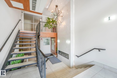 Stairs featuring tile patterned flooring, a towering ceiling, and a chandelier - 310 10606 102 Avenue, Edmonton, AB - Indoor Photo Showing Other Room