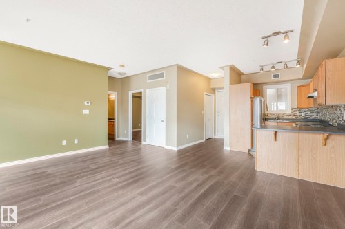 Unfurnished living room with dark wood finished floors and baseboards - 310 10606 102 Avenue, Edmonton, AB - Indoor Photo Showing Kitchen
