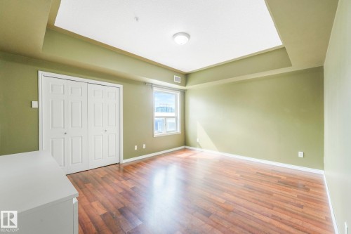 Unfurnished bedroom with dark wood-style floors, a closet, and a tray ceiling - 310 10606 102 Avenue, Edmonton, AB - Indoor Photo Showing Other Room