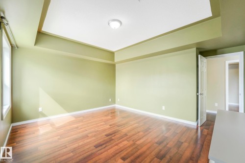 Empty room with dark wood-style flooring and a tray ceiling - 310 10606 102 Avenue, Edmonton, AB - Indoor Photo Showing Other Room