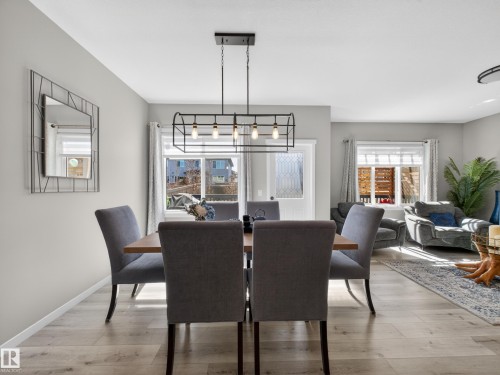 Dining area with wood-finish flooring and a black metal chandelier - 323 Balsam Link, Leduc, AB - Indoor Photo Showing Dining Room